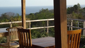 Een houten terras met een tafel en stoelen met uitzicht op zee.