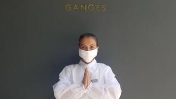 A person in a white dress standing against a dark wall with the text "THE ROSEATE GANGES" above them.