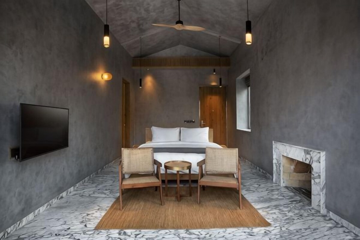 A bedroom with a bed, a television, a fireplace, and a ceiling fan.