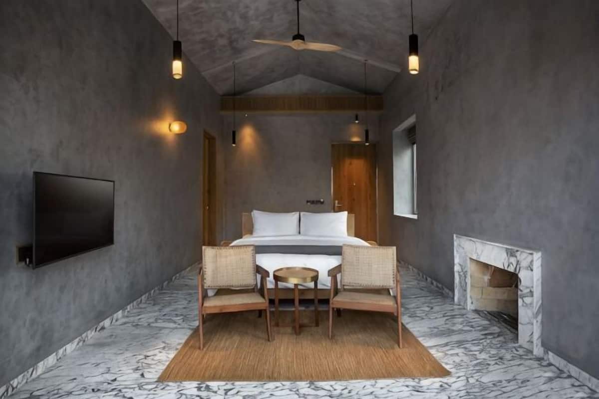 A bedroom with a bed, a television, a fireplace, and a ceiling fan.