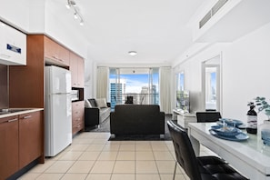 A modern hotel room with a kitchen, dining area, and a balcony with a city view. - Chevron Renaissance - Q Stay (Surfers Paradise)