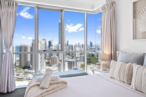 A hotel room with a large window, a bed, a bedside table, and a view of a cityscape. - Chevron Renaissance - Q Stay (Surfers Paradise)