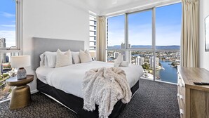 A modern hotel room with a large bed, a view of the city, and a desk with a remote control. - Chevron Renaissance - Q Stay (Surfers Paradise)