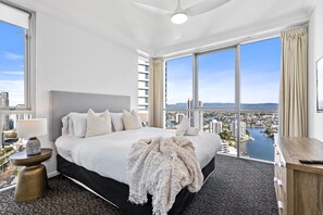 A modern hotel room with a large bed, a view of the city, and a desk with a remote control. - Chevron Renaissance - Q Stay (Surfers Paradise)