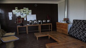 Un salon doté d’un parquet en bois foncé, d’un canapé, d’une table basse et d’une cheminée. Plusieurs tableaux encadrés ornent le mur, et une horloge y est également accrochée.