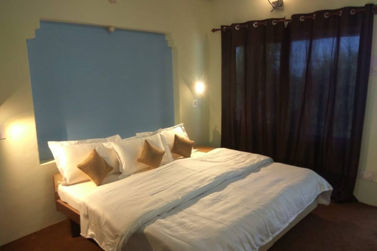 A bedroom with a bed, pillows, a window, and curtains.