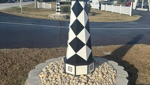 A lighthouse with a black and white diamond pattern, surrounded by a stone base and a white picket fence. - Bogue Shores, King bed. Pool side, Beach and Sound Access-sleeps 4 (Atlantic Beach)