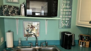 A kitchen with teal walls, a double sink, a microwave, and a coffee maker. - Bogue Shores, King bed. Pool side, Beach and Sound Access-sleeps 4 (Atlantic Beach)