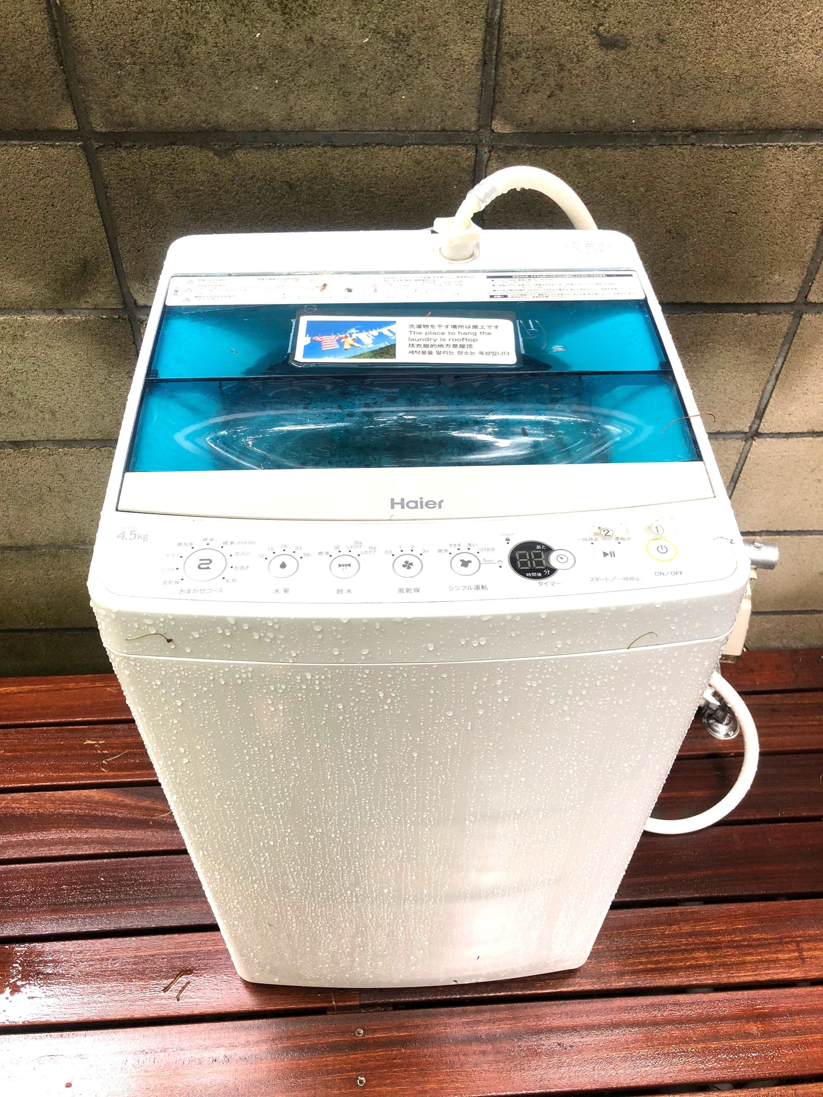 A white Haier water purifier with a transparent water tank, control panel, and a handle on top.