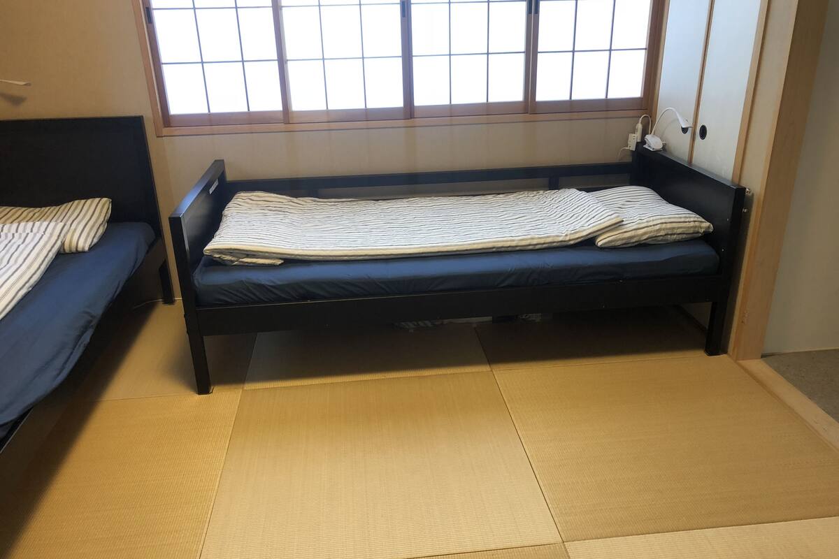 A room with two bunk beds, a tatami mat floor, and a window with a grid pattern.