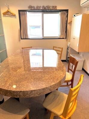 A room with a round marble table, wooden chairs, a window with curtains, and a wardrobe. - Tokyo Art House (Tokyo)