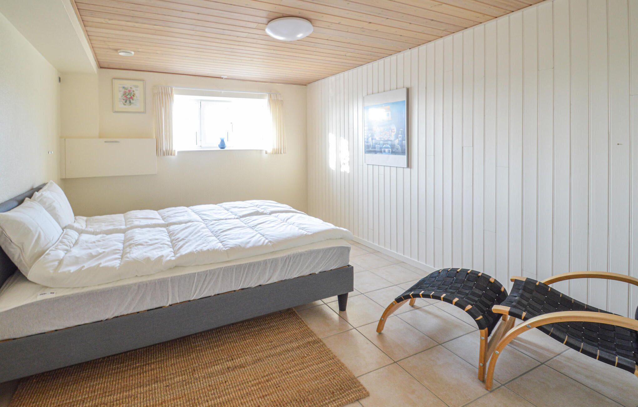 A bedroom with a bed, a window, a chair, and a rug.