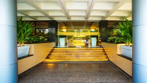 A hotel lobby with a central staircase, potted plants, and a reception desk. - Mastiff Hotel Chinchwad by OTHPL (Pune)
