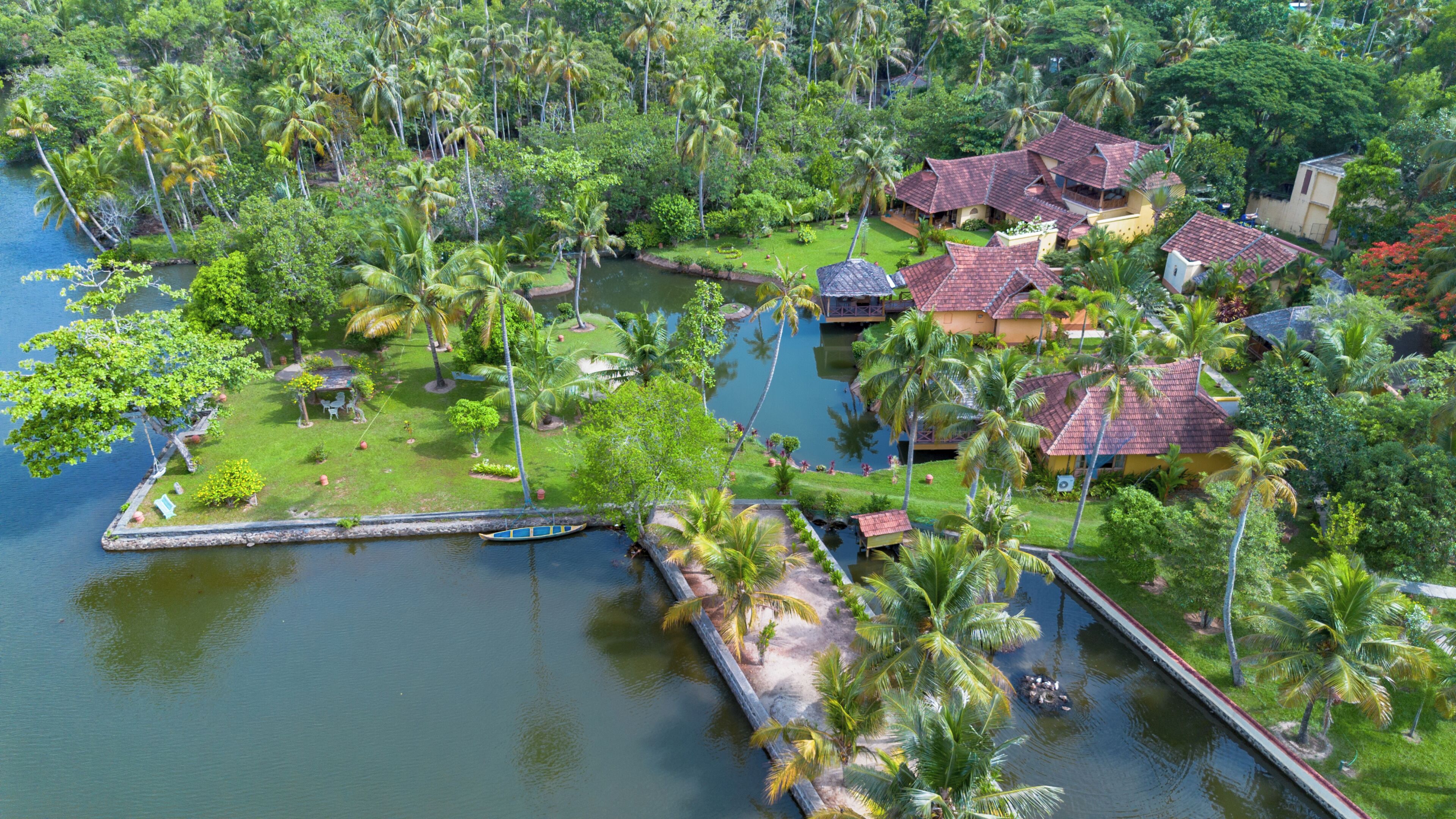 Un resort tropical con varias edificaciones tipo bungalow, una masa de agua central y abundante vegetación.