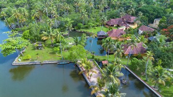Un resort tropical con varias edificaciones tipo bungalow, una masa de agua central y abundante vegetación.