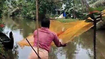 A man standing by a river, holding a net.