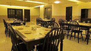 A spacious dining area with multiple tables and chairs, equipped with ceiling fans and recessed lighting. - Hotel La Residence (Gurugram)