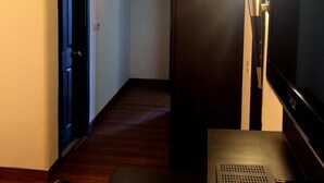A hotel room with a wooden floor, a TV, a desk with a computer, and a lamp. - Hotel La Residence (Gurugram)