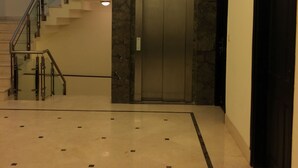 A modern interior with a marble floor, a staircase, a ceiling fan, and an elevator. - Hotel La Residence (Gurugram)