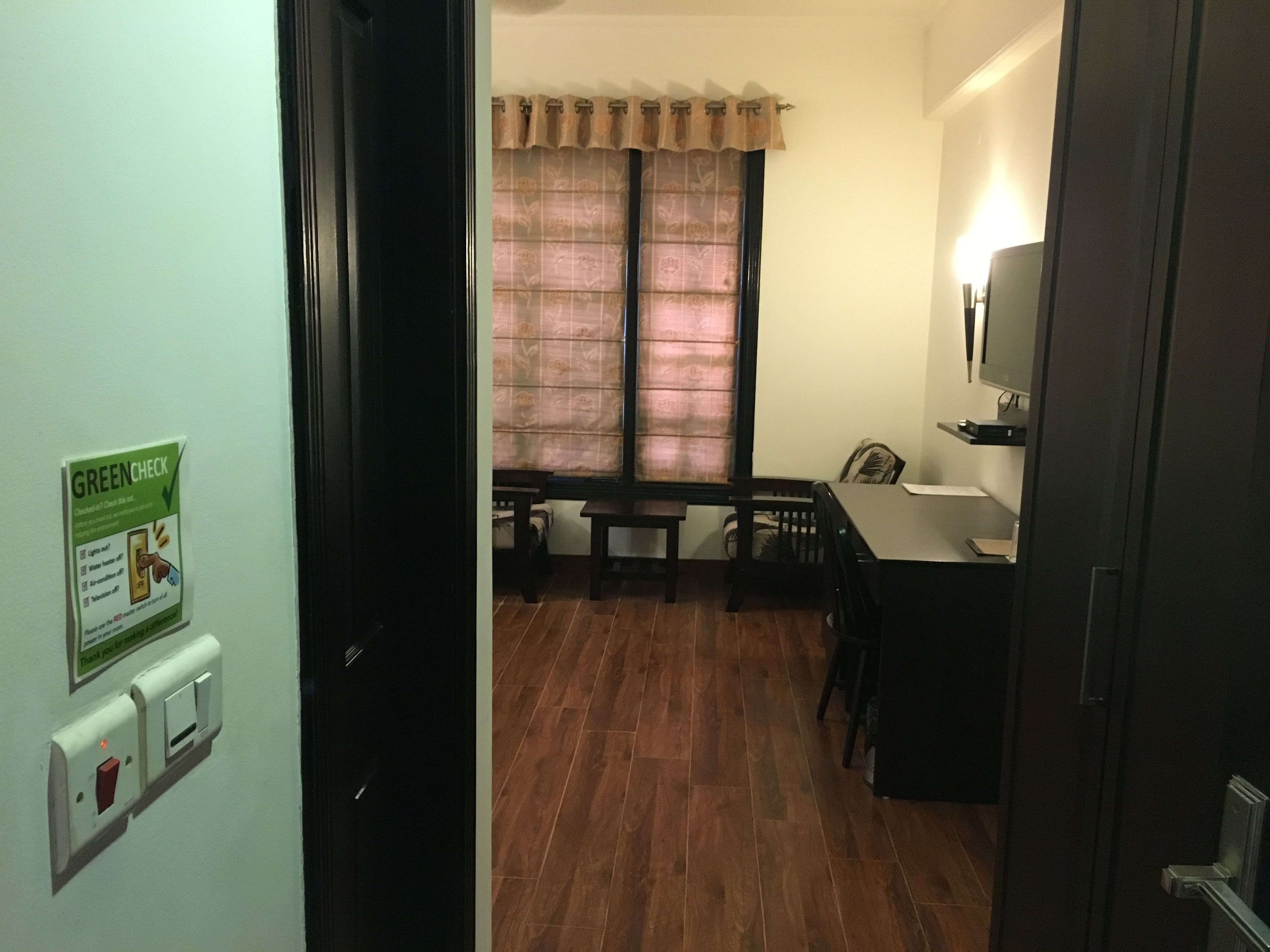 A room with a dining area, a television on the wall, and a green 'Green Check' sign on the wall.