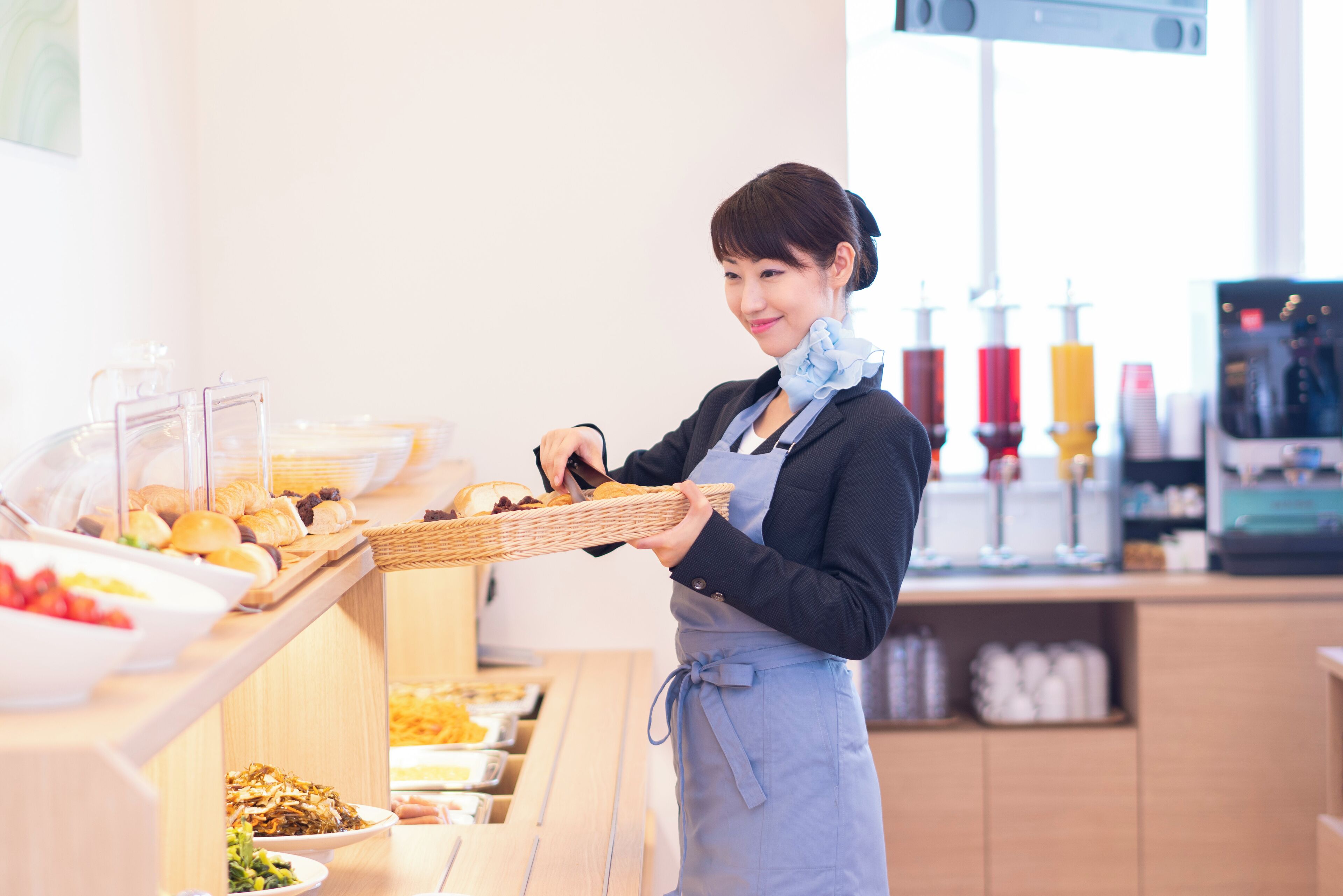A buffet setup with various food items and a person serving.
