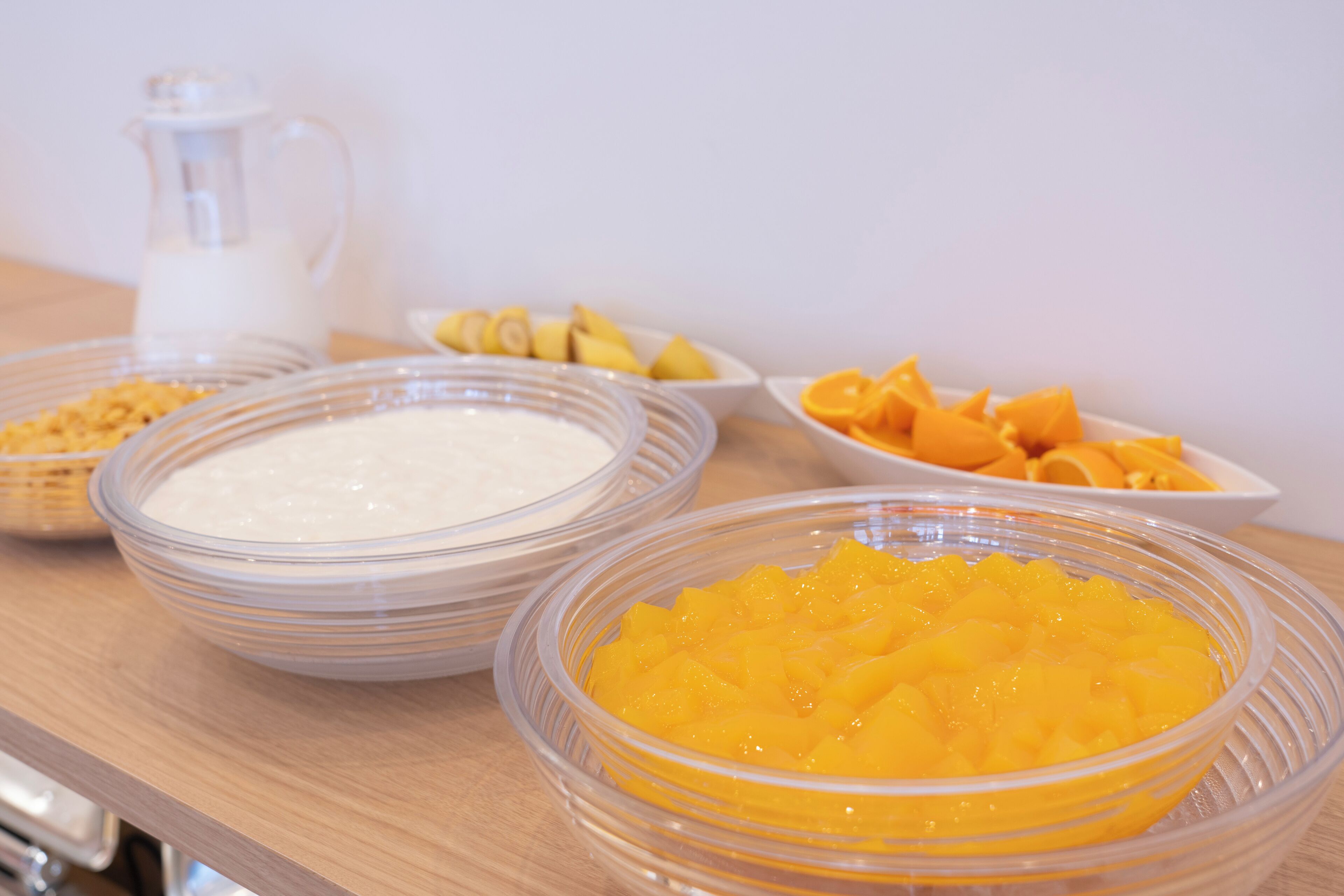 A table with bowls of food, including a white creamy substance and diced mangoes.
