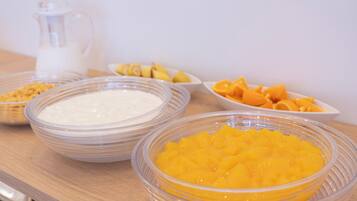 A table with bowls of food, including a white creamy substance and diced mangoes.