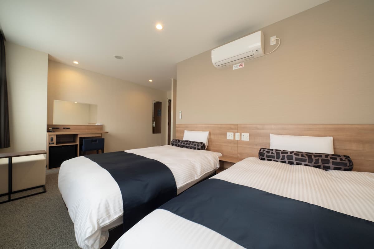 Habitación de hotel con dos camas, un escritorio y una silla.
