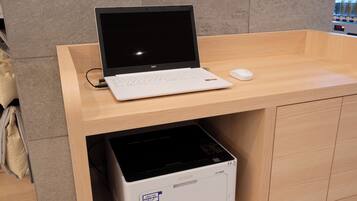 A laptop on a wooden desk with a printer underneath.
