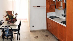 Eine kleine Küche mit Holzschränken, einer Arbeitsplatte und einem an der Wand befestigten Fernseher.