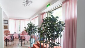 Eine Hotelhalle mit Treppe, Essbereich und Topfpflanzen.