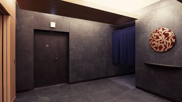 A modern hallway with dark tiled walls, a wooden door, and a blue curtain.