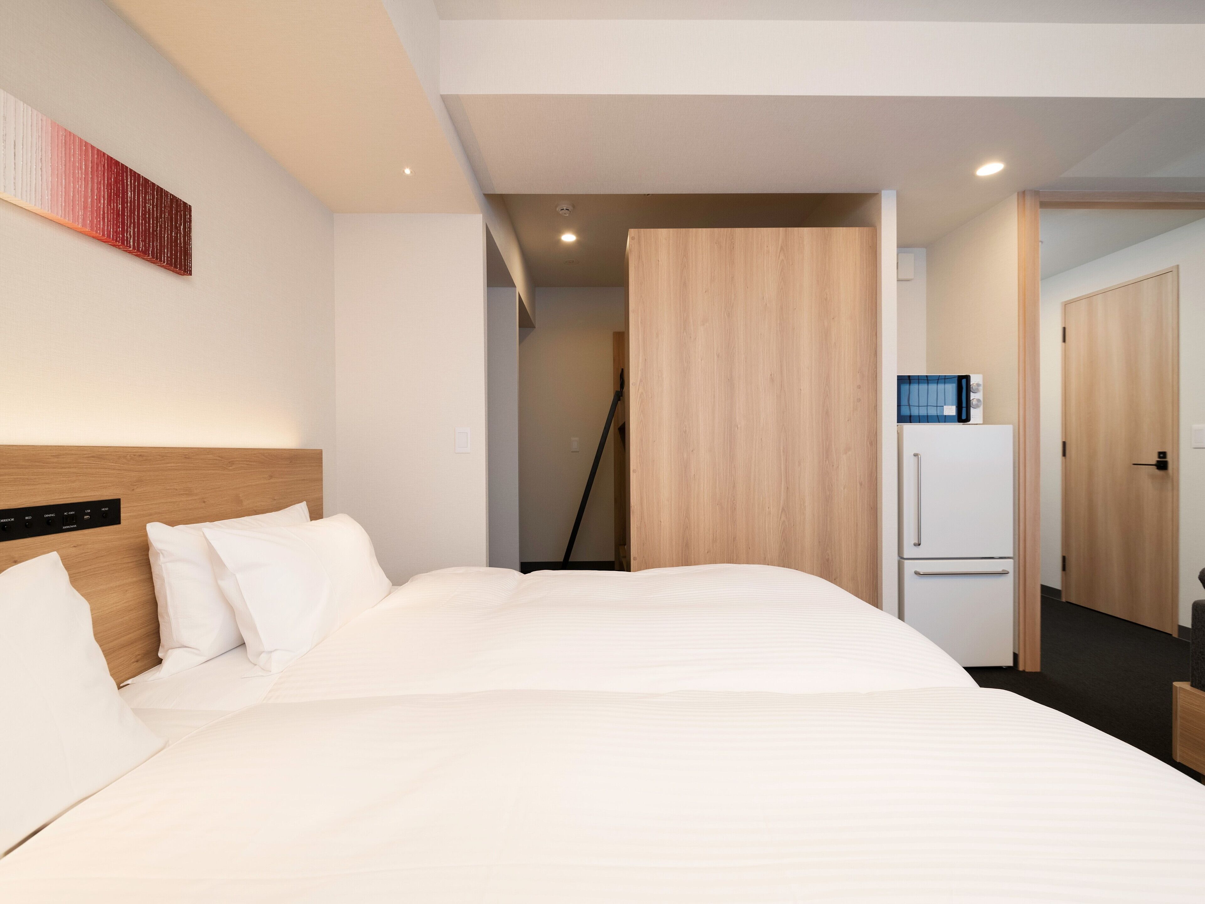Habitación de hotel con una cama grande, cabecera de madera, televisión de pantalla plana, refrigerador y microondas.