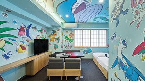 Habitación infantil con televisión, literas y paredes decoradas con personajes de dibujos animados.