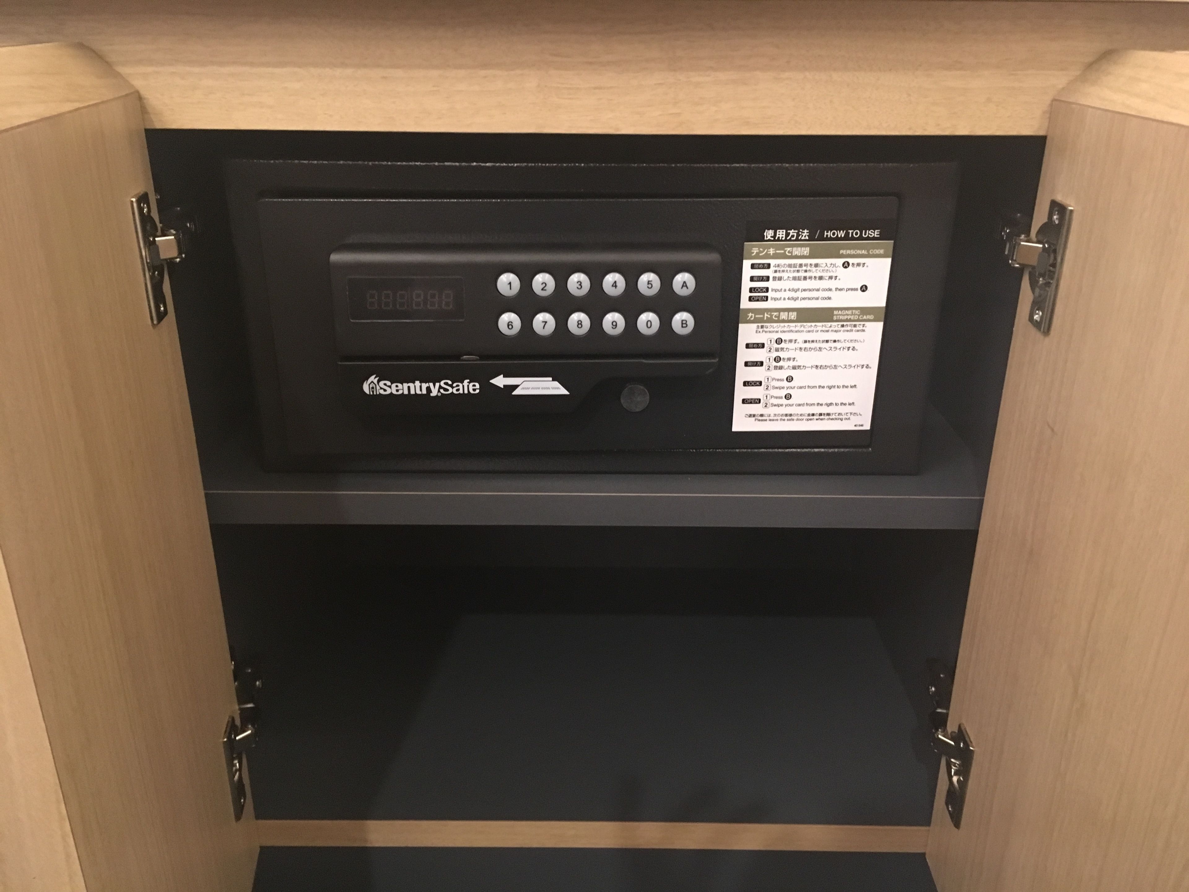 A black electronic device with a keypad and a screen, labeled "SentrySafe," inside a wooden cabinet.