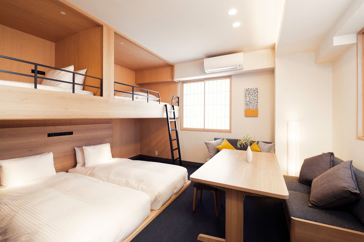 Quarto com beliche, escrivaninha e sofá.