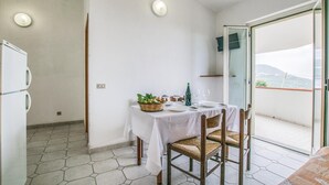 Ein Balkon mit Esstisch, Kühlschrank und Blick auf die Landschaft.