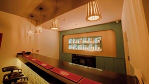 Un espace bar avec un comptoir, des suspensions décoratives et une étagère où sont exposées des bouteilles.