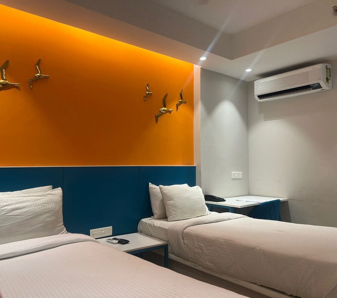 Habitación de hotel con dos camas, aire acondicionado de pared y una mesita con un control remoto.