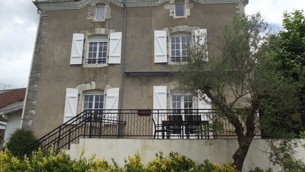 A two-story building with a balcony and a staircase leading up to it.