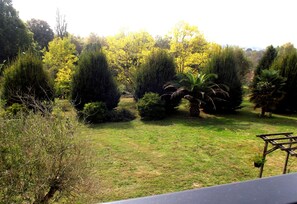 A garden with various trees and shrubs, a grassy area, and a wooden structure. - Chambres d'Hôtes de Poumatan (Rivière-Saas-et-Gourby)