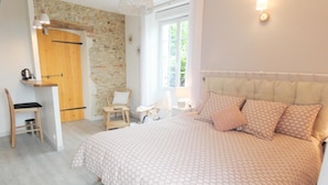 Un dormitorio con una cama grande, un escritorio de madera, una silla y una pared de piedra.