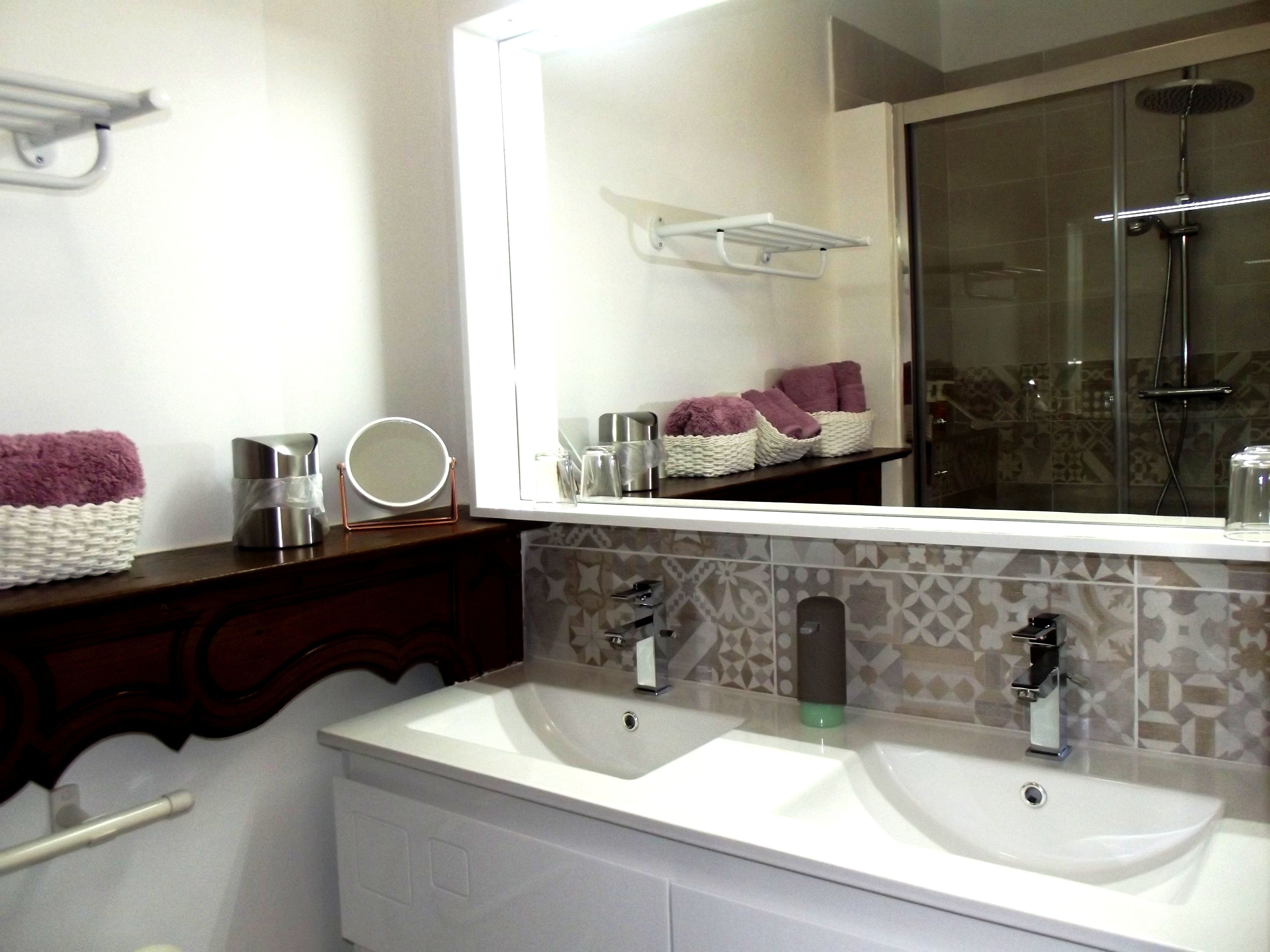 A bathroom with two sinks, a large mirror, and a shower area.