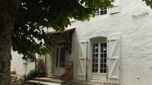 Un edificio blanco con una escalera de piedra que conduce a una puerta con contraventanas blancas.