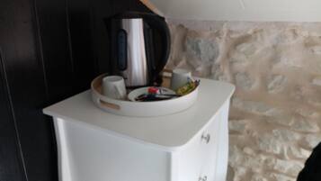 Ett litet pentry med ett vitt skåp, en vattenkokare, en mugg och en skål med snacks.