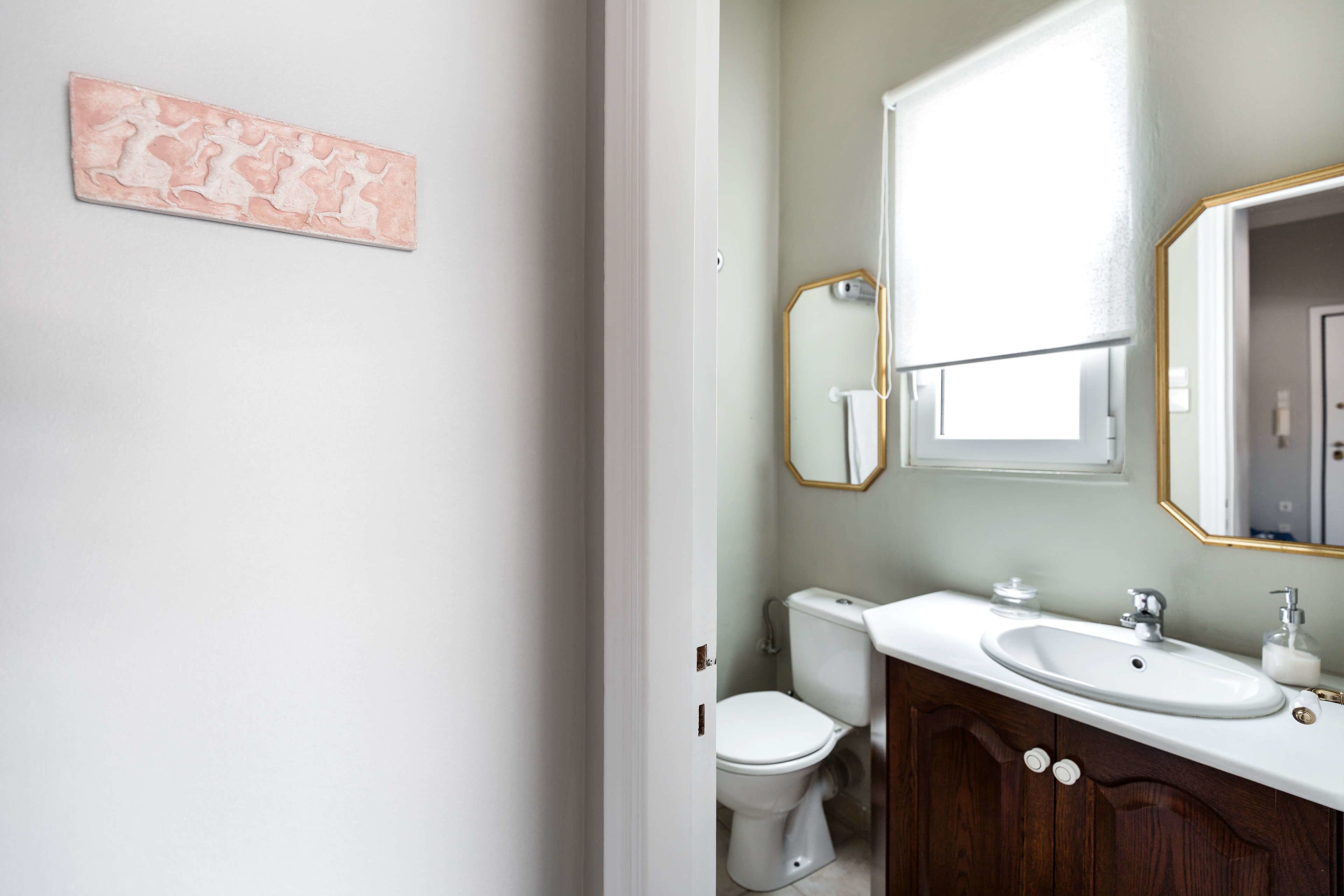 A bathroom with a white toilet, a white sink, and a wooden vanity.