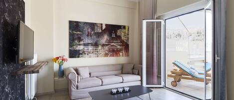 A modern living room with a sofa, a coffee table, a TV, and a painting on the wall.