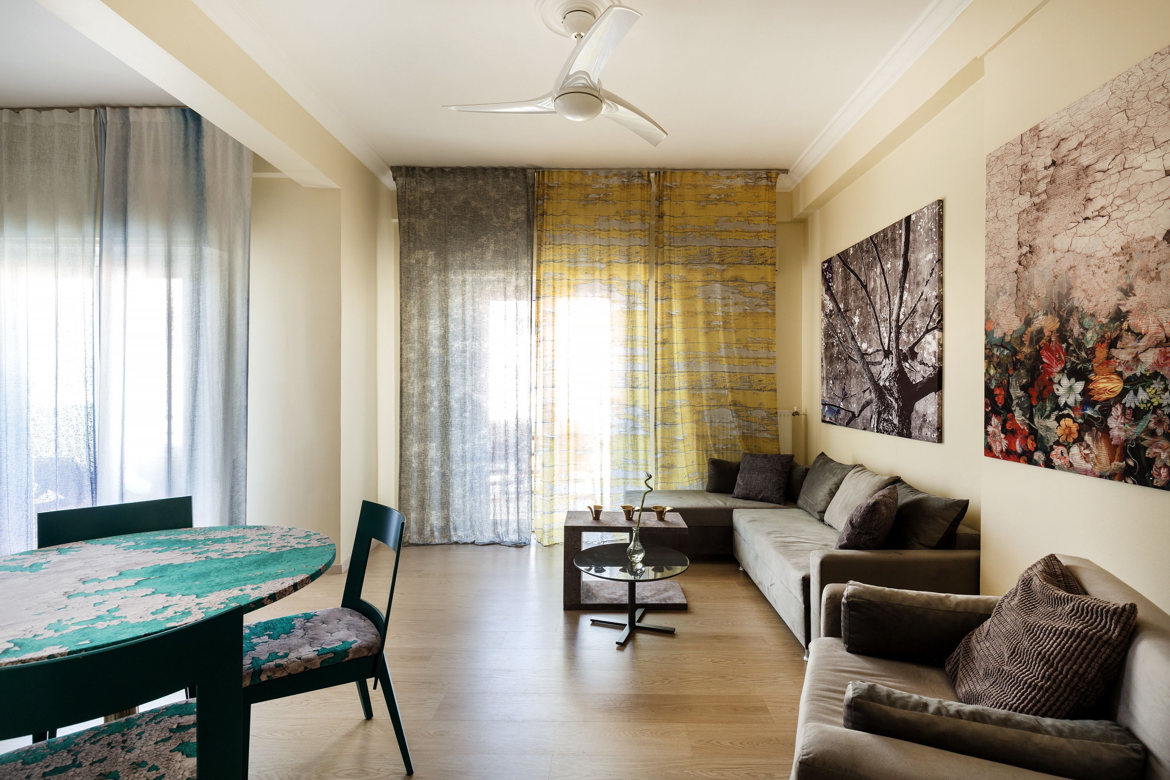 A living room with a round table, a sofa, and a ceiling fan.