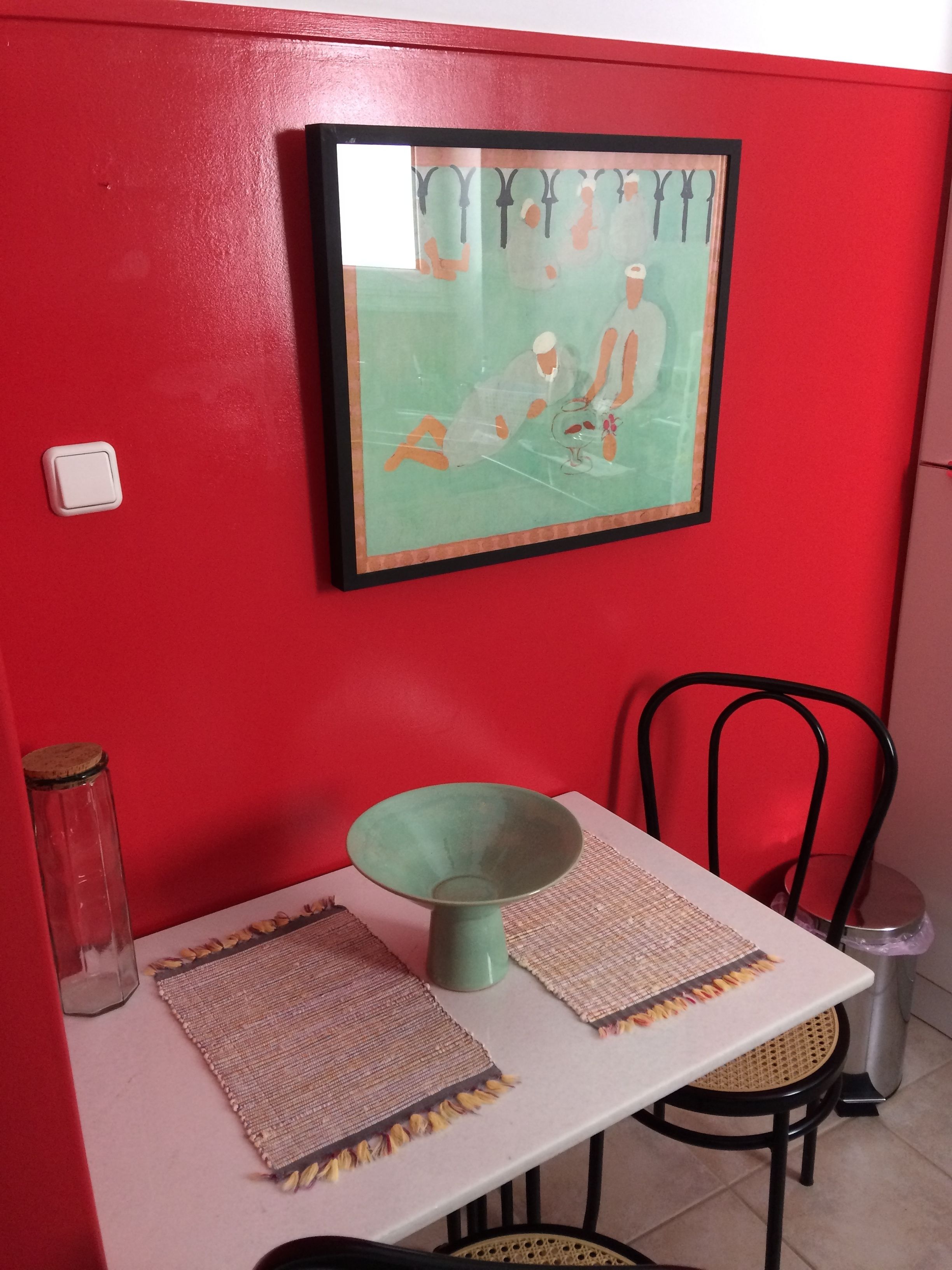 A dining area with a table, chairs, a framed artwork, and a vase.