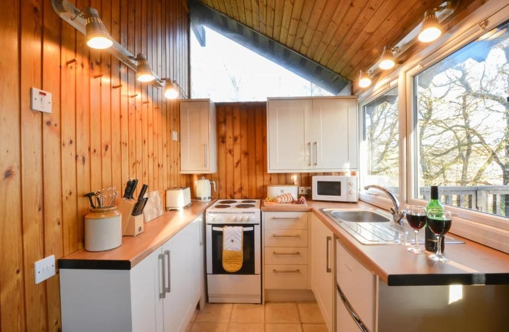 Een compacte keuken met houten wanden, een fornuis, een magnetron en een spoelbak.